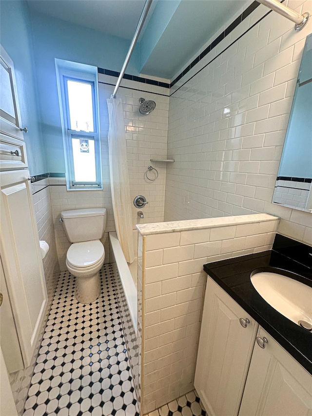 bathroom with toilet, tile patterned floors, tile walls, wainscoting, and vanity