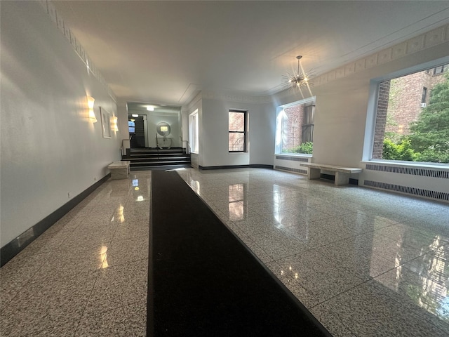 interior space with crown molding, radiator heating unit, baseboards, and granite finish floor