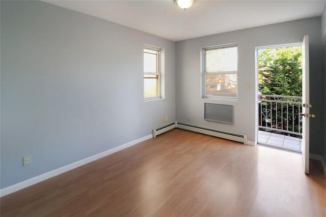 unfurnished room featuring plenty of natural light, wood finished floors, baseboards, and a baseboard heating unit