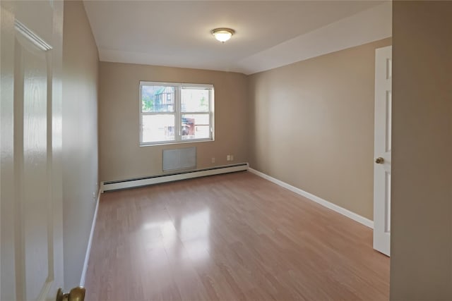 empty room featuring wood finished floors, baseboards, and a baseboard heating unit