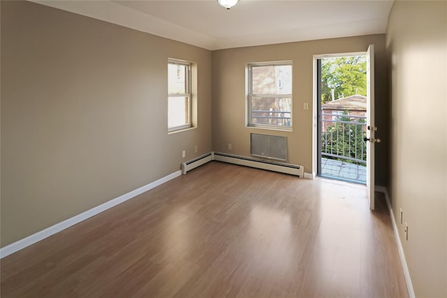unfurnished room with baseboards, wood finished floors, and a baseboard radiator