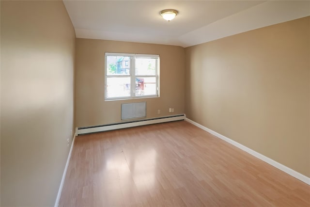spare room with light wood-type flooring, baseboards, and a baseboard heating unit