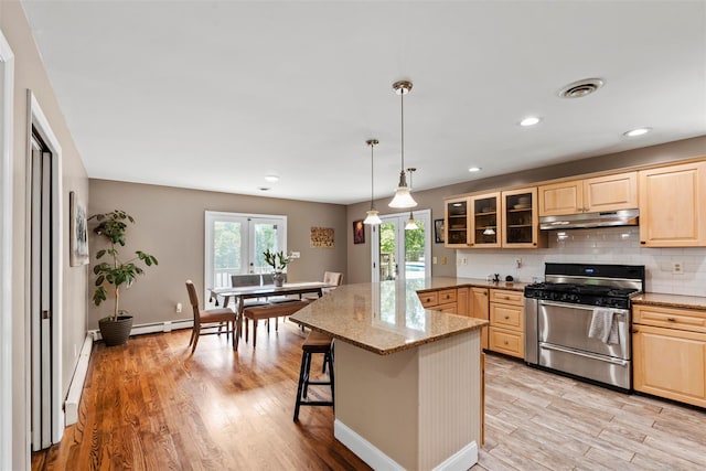 10 Spectrum Dr, Chester, NY 10918 - kitchen featuring stainless steel range with gas stovetop, under cabinet range hood, light brown cabinetry, glass insert cabinets, and baseboard heating