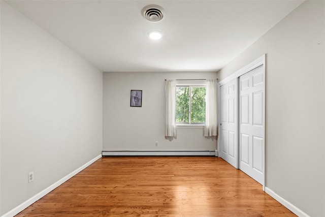 10 Spectrum Dr, Chester, NY 10918 - unfurnished bedroom with baseboard heating, light wood finished floors, baseboards, and a closet