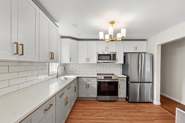 315 Scotchtown Rd, Goshen, NY 10924 - kitchen with appliances with stainless steel finishes, a sink, a chandelier, tasteful backsplash, and light wood-type flooring