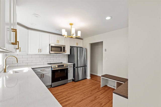 315 Scotchtown Rd, Goshen, NY 10924 - kitchen with appliances with stainless steel finishes, a sink, a chandelier, tasteful backsplash, and light wood-type flooring