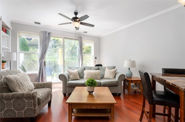 living room featuring visible vents, a ceiling fan, ornamental molding, and dark wood-style floors