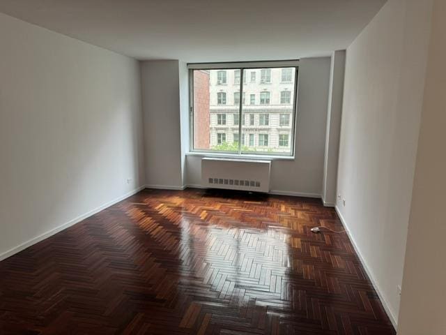 spare room featuring baseboards and radiator heating unit
