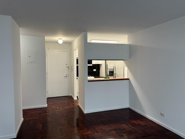 interior space featuring stainless steel fridge with ice dispenser and baseboards