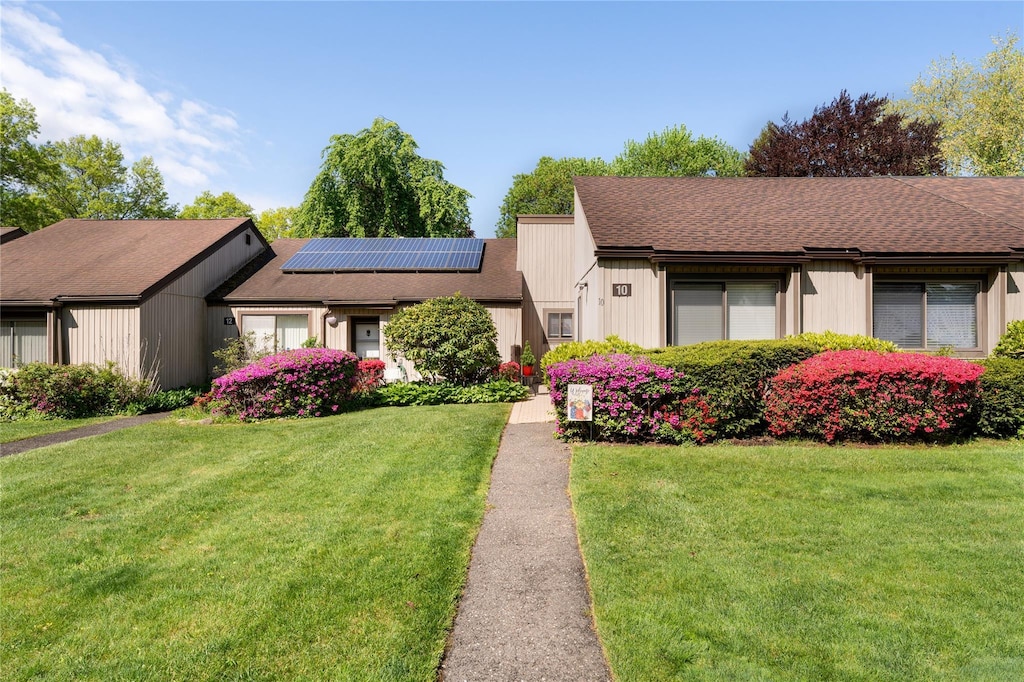 10 Strathmore Gate Dr, Stony Brook, NY 11790 - mid-century home featuring a front yard, solar panels, and roof with shingles