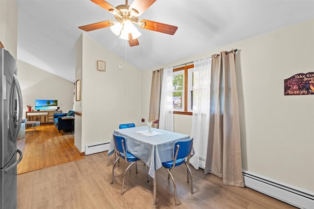 dining space featuring a baseboard heating unit, vaulted ceiling, a ceiling fan, and light wood-style flooring