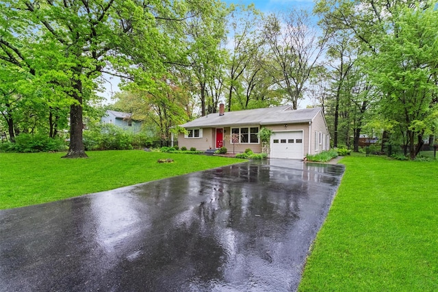 ranch-style house featuring driveway, an attached garage, a chimney, and a front yard