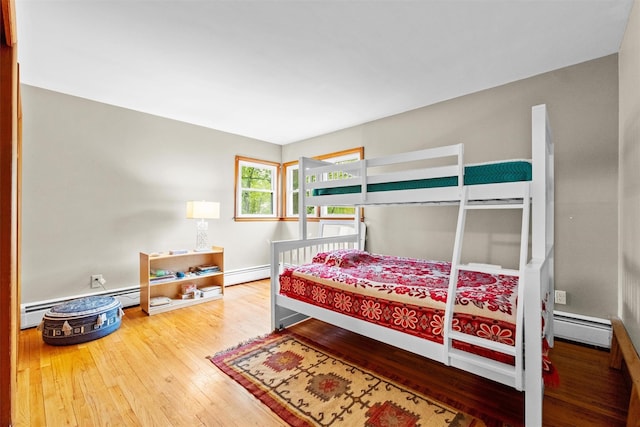 bedroom with a baseboard heating unit and wood-type flooring