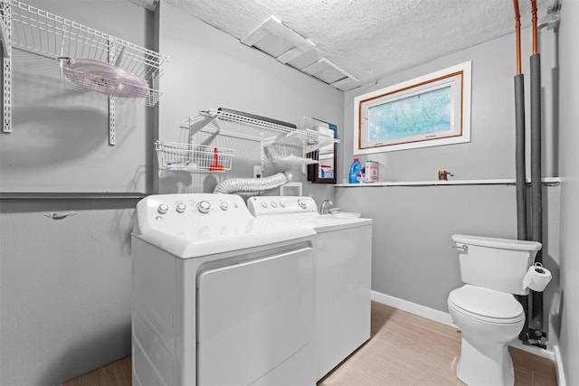 washroom featuring washing machine and clothes dryer, a textured ceiling, and baseboards
