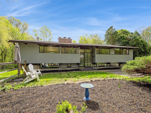back of house featuring a chimney and a sunroom