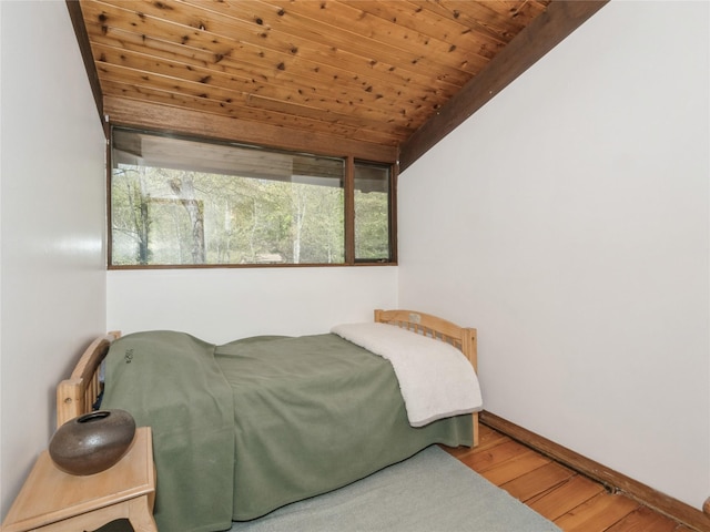 bedroom with wood finished floors, multiple windows, wooden ceiling, baseboards, and vaulted ceiling
