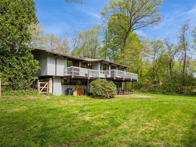 back of house with a yard, a wooden deck, and a chimney