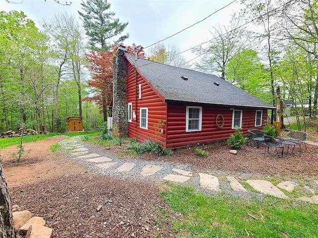 112 E Thompson Pl, Smallwood, NY 12778 - view of home's exterior with a shingled roof, a shed, an outdoor structure, log veneer siding, and a chimney