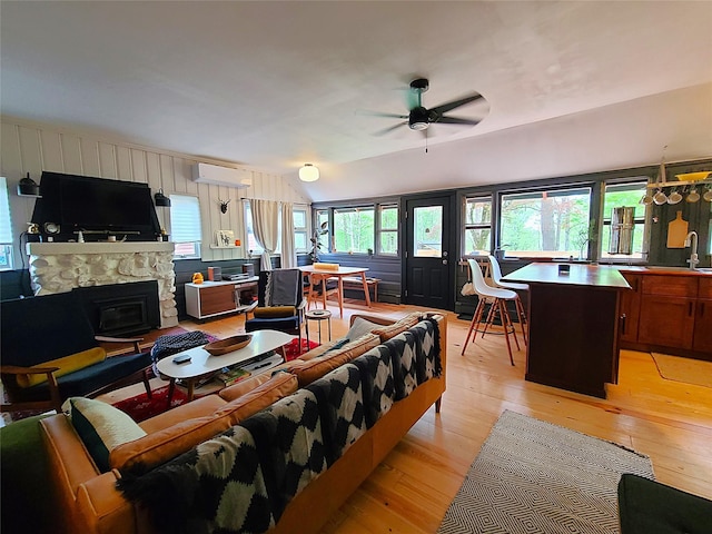 112 E Thompson Pl, Smallwood, NY 12778 - living room featuring a wall mounted AC, light wood-type flooring, ceiling fan, vaulted ceiling, and a stone fireplace
