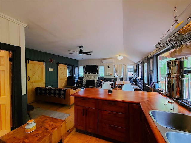 112 E Thompson Pl, Smallwood, NY 12778 - kitchen with light wood-style floors, a stone fireplace, a wall mounted AC, ceiling fan, and wooden counters