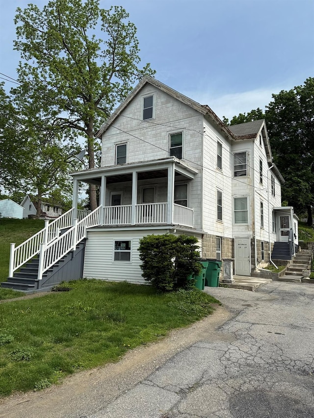 view of front facade featuring stairs, asphalt driveway, and a front lawn