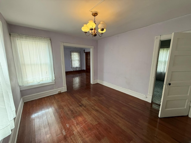 unfurnished dining area featuring a chandelier, hardwood / wood-style flooring, and baseboards