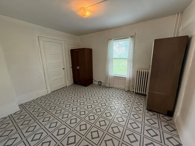 spare room featuring radiator and light tile patterned floors