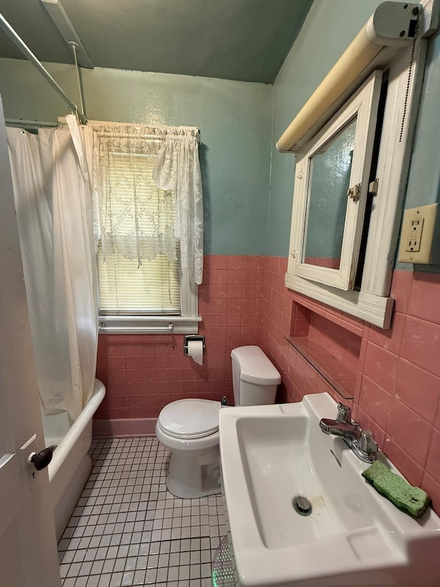 full bathroom featuring tile walls, tile patterned floors, a sink, toilet, and a wainscoted wall