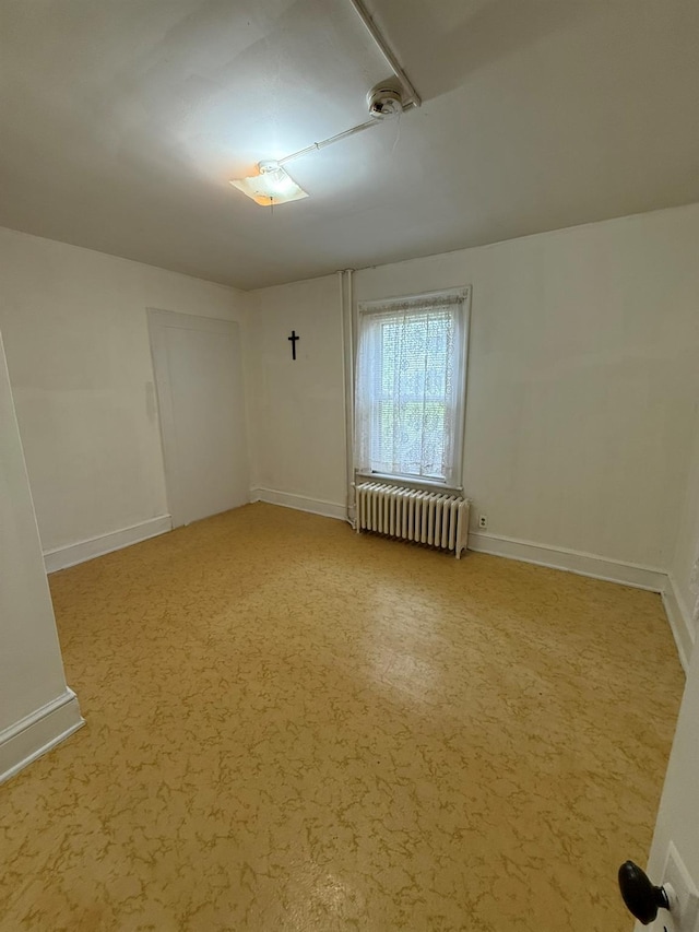 empty room featuring radiator and baseboards