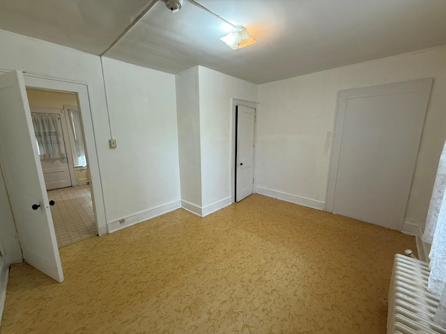 unfurnished bedroom with radiator heating unit and baseboards