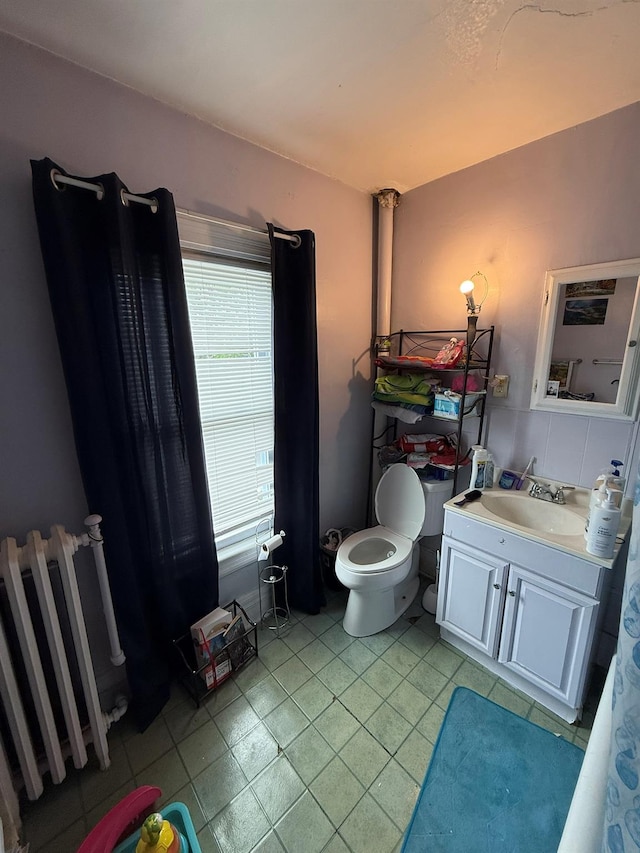 bathroom with radiator heating unit, tile patterned flooring, toilet, and vanity