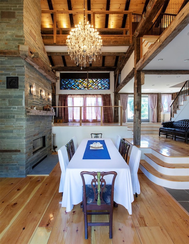 5 Downer Ln, Woodstock, NY 12498 - dining room featuring beam ceiling, high vaulted ceiling, an inviting chandelier, wood-type flooring, and a stone fireplace