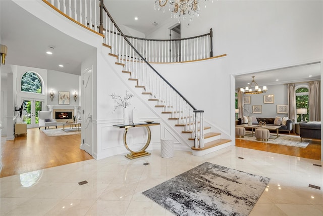 9 Oak Ridge Ct, West Harrison, NY 10604 - entrance foyer with a high ceiling, a chandelier, stairs, a lit fireplace, and crown molding