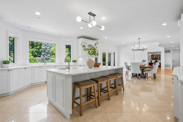 9 Oak Ridge Ct, West Harrison, NY 10604 - kitchen featuring a sink, a chandelier, an island with sink, white cabinets, and light countertops