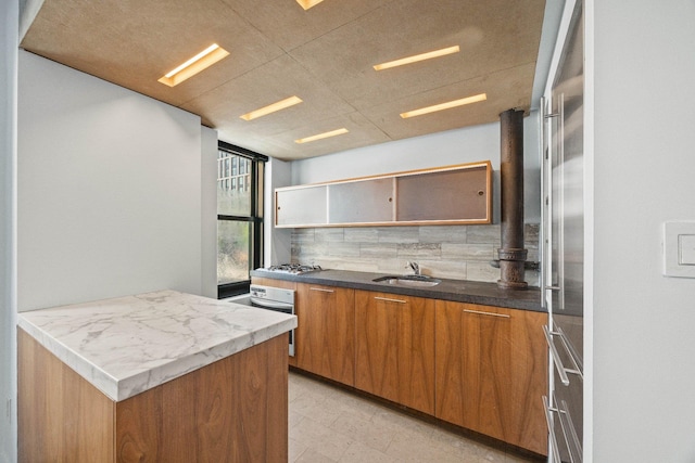 kitchen with a sink, open shelves, decorative backsplash, brown cabinets, and oven