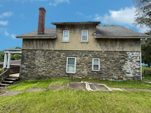 17 Springside Ave, Poughkeepsie, NY 12603 - back of house featuring stone siding, a chimney, a lawn, and roof with shingles