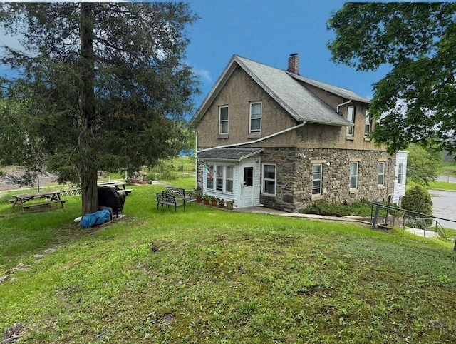 17 Springside Ave, Poughkeepsie, NY 12603 - rear view of house featuring stone siding, stucco siding, a lawn, and a chimney