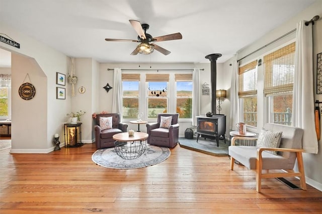 sitting room featuring a wood stove, light wood-style flooring, and a healthy amount of sunlight