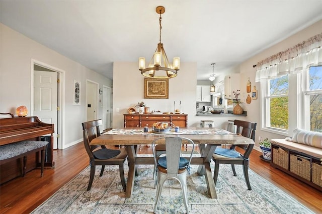 dining space with baseboards, an inviting chandelier, and wood finished floors