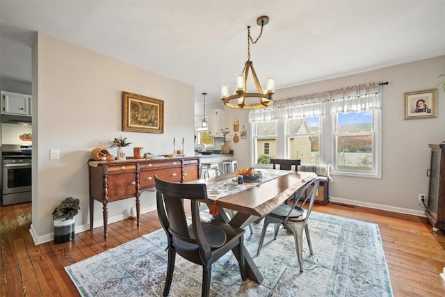 dining area with baseboards, an inviting chandelier, and wood-type flooring