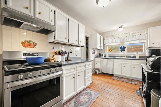 kitchen with light wood-type flooring, under cabinet range hood, white cabinets, dark countertops, and appliances with stainless steel finishes