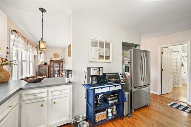 kitchen featuring freestanding refrigerator, a toaster, light wood finished floors, and white cabinets