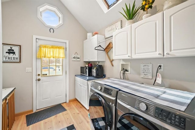 laundry room featuring washer and dryer, light wood-style flooring, cabinet space, a skylight, and baseboards