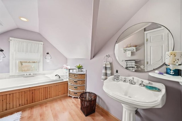 bathroom with lofted ceiling and wood finished floors