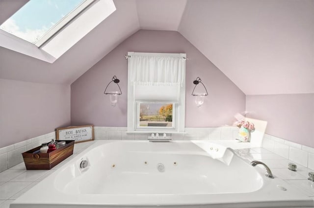 bathroom with a tub with jets and vaulted ceiling with skylight