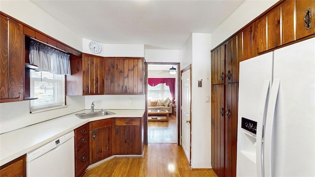 kitchen with white appliances, a sink, light countertops, light wood-style floors, and a ceiling fan