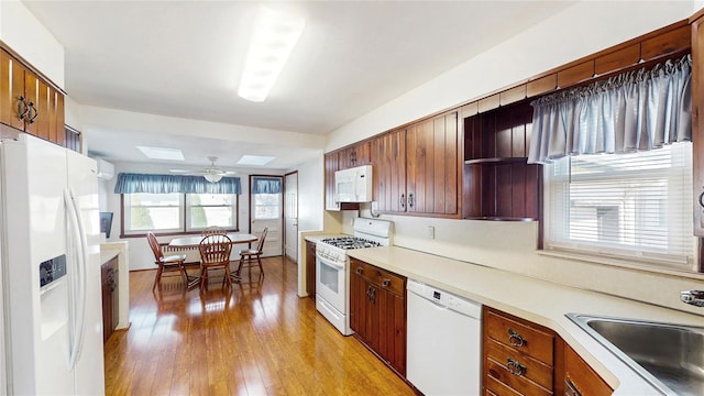kitchen with white appliances, a skylight, a sink, open shelves, and light wood finished floors