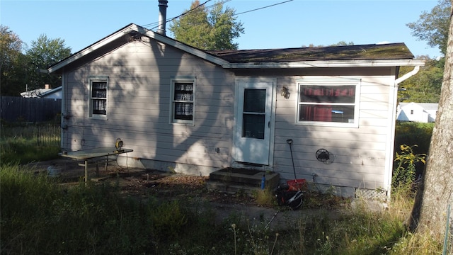 rear view of property with entry steps and fence
