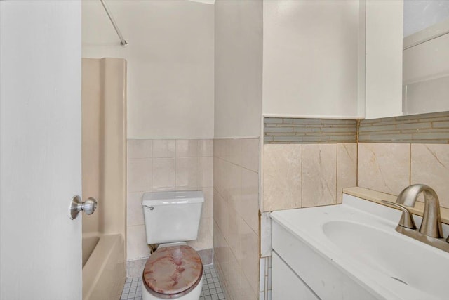 full bathroom with tile walls, toilet, vanity, and a wainscoted wall