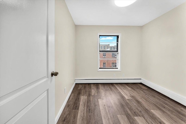 empty room with baseboard heating, wood finished floors, and baseboards